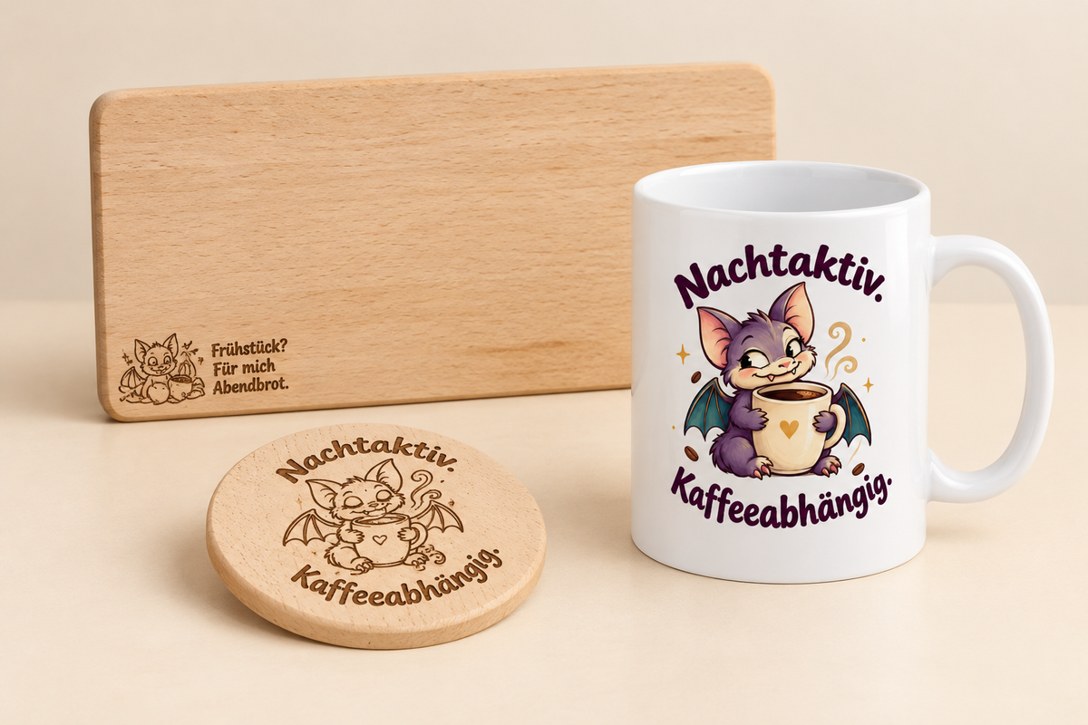 „Dreiteiliges Fledermaus-Geschenkset mit Tasse und dem Spruch ‚Nachtaktiv. Kaffeeabhängig.‘ sowie graviertem Holzbrettchen und Untersetzer.“